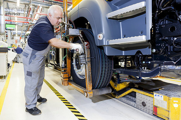 Mitarbeiter bei der Montage der Reifen am Fahrgestell  bei der MAN Truck und Bus AG  München  Oberbayern  Bayern  Deutschland