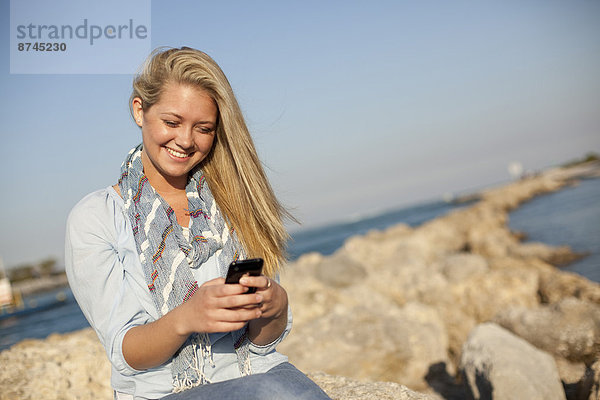Vereinigte Staaten von Amerika  USA  Felsbrocken  sitzend  Frau  Kurznachricht  Strand  Telefon  jung  Handy  Florida