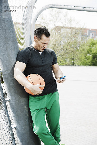 stehend  Mann  sehen  Spiel  reifer Erwachsene  reife Erwachsene  Basketball  MP3-Player  MP3 Spieler  MP3 Player  MP3-Spieler  Außenaufnahme  Gericht  Deutschland