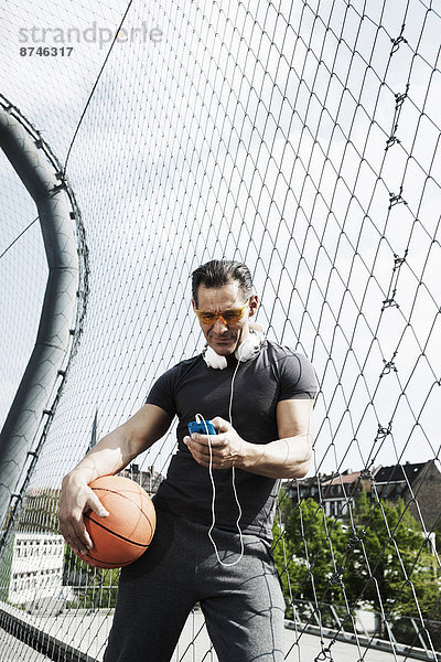 stehend  Mann  sehen  halten  Spiel  reifer Erwachsene  reife Erwachsene  Basketball  MP3-Player  MP3 Spieler  MP3 Player  MP3-Spieler  Außenaufnahme  Gericht  Deutschland