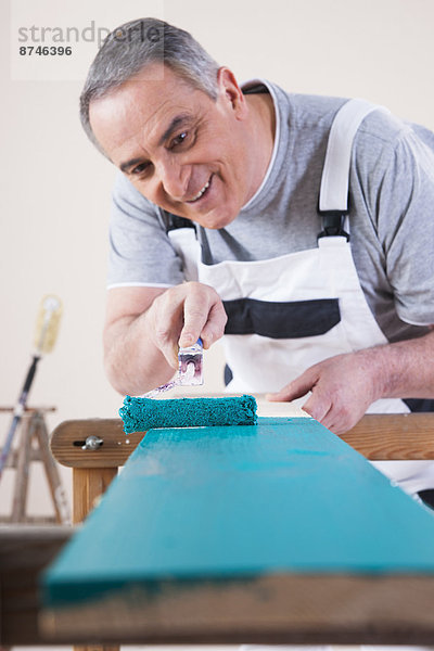 Studioaufnahme Senior Senioren einsteigen Mann blau streichen streicht streichend anstreichen anstreichend Farbe Farben bemalen