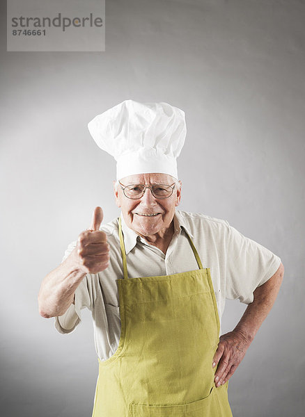 hoch  oben  Studioaufnahme  Senior  Senioren  Mann  geben  Hut  Schürze  Koch  Menschlicher Daumen  Menschliche Daumen