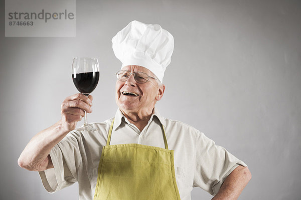 Studioaufnahme Senior Senioren Mann Hut Rotwein Schürze Kleidung Koch
