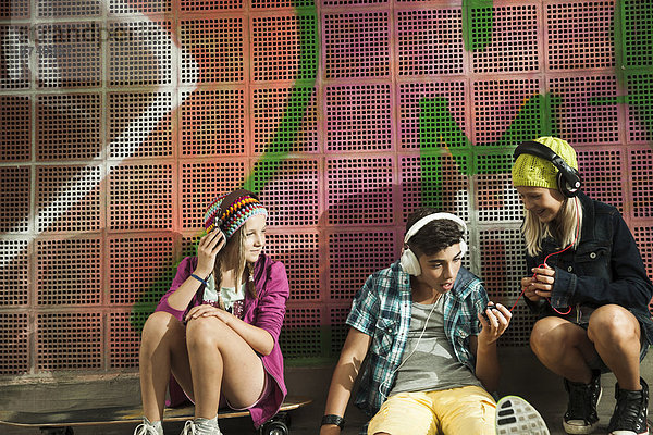 Außenaufnahme  sitzend  zuhören  Wand  Kopfhörer  Musik  Kleidung  Deutschland  freie Natur