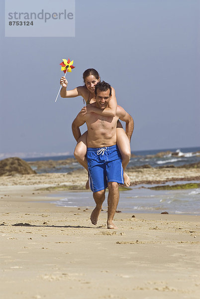Mann die Frau auf Schultern am Strand