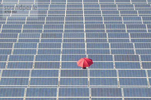 Frau hält red Umbrella in Solaranlage