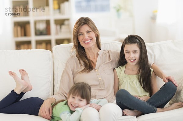 Mother and daughters (4-5 8-9) sitting on sofa