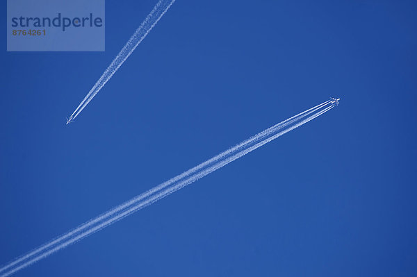 Zwei Flugzeuge mit Kondensstreifen am blauen Himmel  Bayern  Deutschland