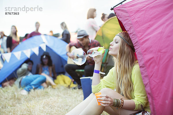 Frau bläst Blasen aus dem Zelt beim Musikfestival