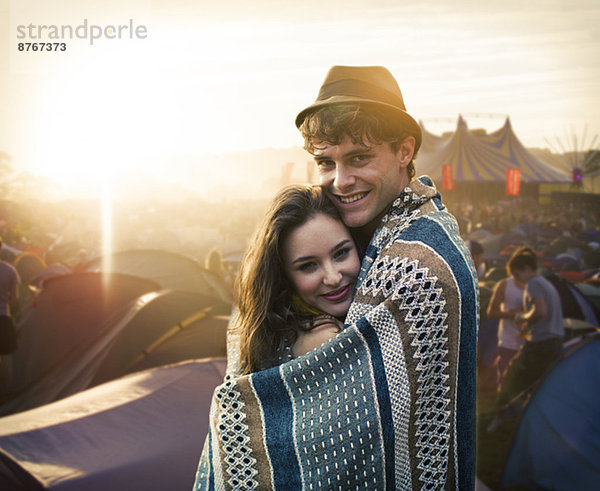 Paar in eine Decke gewickelt außerhalb der Zelte beim Musikfestival