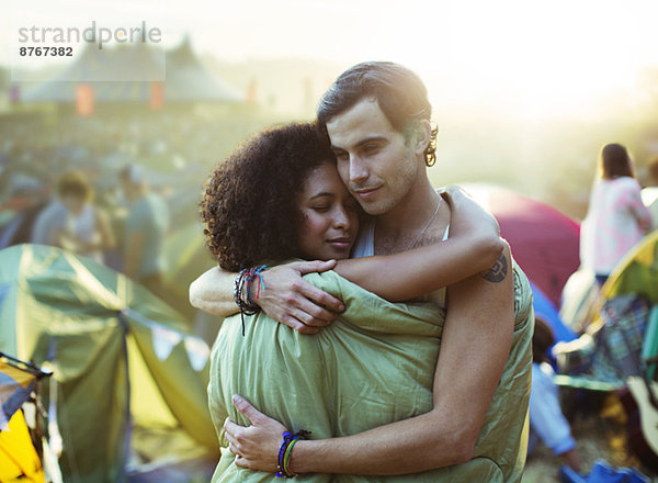 Paar im Schlafsack beim Musikfestival vor den Zelten