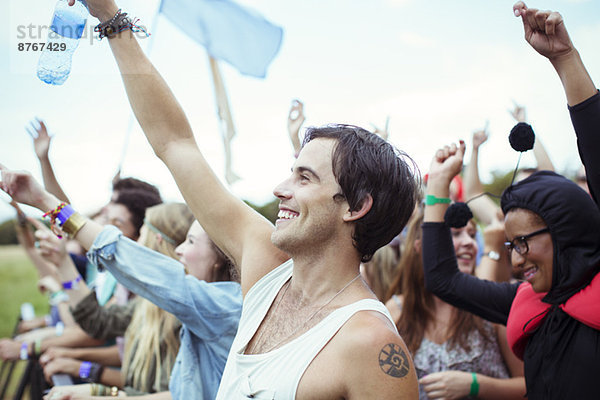 Mann mit Wasserflasche jubelt beim Musikfestival