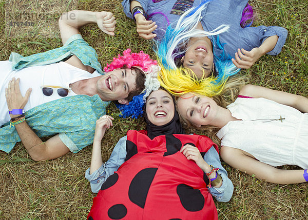 Portrait von Freunden in Kostümen  die beim Musikfestival im Gras liegen.