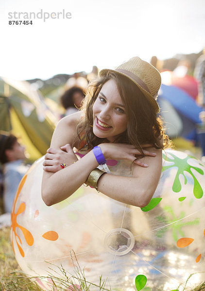 Porträt einer glücklichen Frau  die sich auf einem aufblasbaren Stuhl vor den Zelten des Musikfestivals stützt.