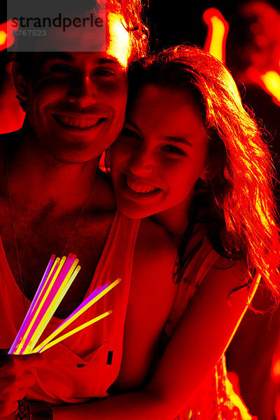 Nahaufnahme Porträt eines glücklichen Paares mit Leuchtstäben beim Musikfestival