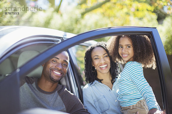 Porträt einer glücklichen Familie innerhalb und außerhalb des Autos