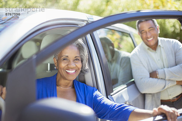 Porträt eines glücklichen älteren Paares innerhalb und außerhalb des Autos