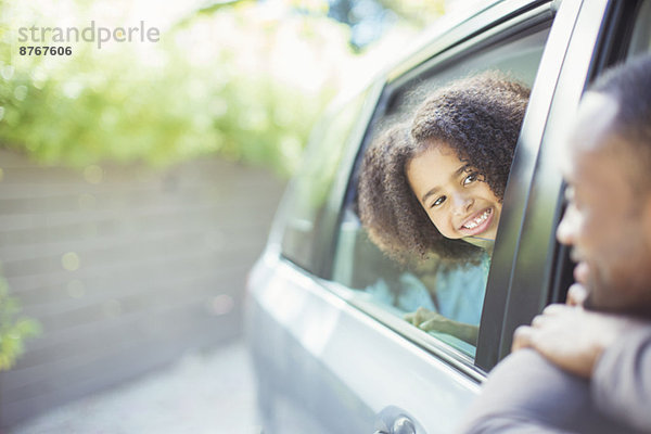 Vater und Tochter lehnen sich aus den Autoscheiben.