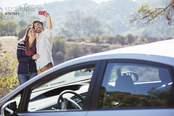 Selbstporträt eines Paares mit Handy außerhalb des Autos