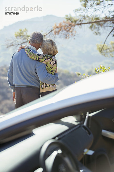 Seniorenpaar mit Blick auf die Berge außerhalb des Autos