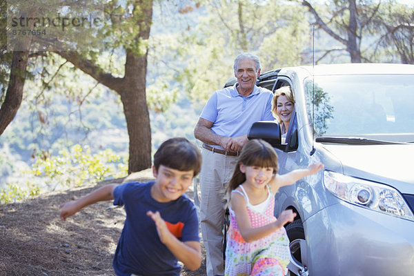 Großeltern beobachten Enkelkinder  die außerhalb des Autos rennen.