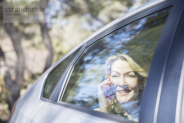 Seniorenfrau spricht am Handy im Auto