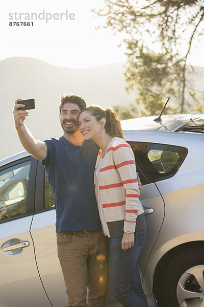 Selbstporträt eines Paares mit Fotohandy außerhalb des Autos