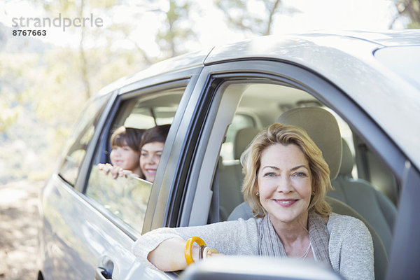 Porträt der glücklichen Großmutter und Enkelkinder an den Autofenstern