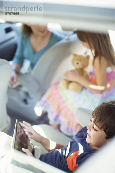 Junge mit digitalem Tablett auf dem Rücksitz des Autos