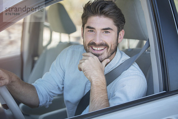 Porträt eines lächelnden Mannes beim Autofahren