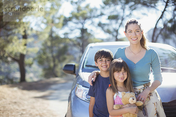 Porträt einer glücklichen Familie  die sich auf das Auto stützt.
