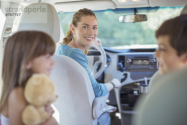 Porträt der lächelnden Mutter mit Familie im Auto