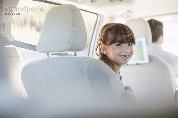 Porträt des lächelnden Mädchens auf dem Rücksitz des Autos