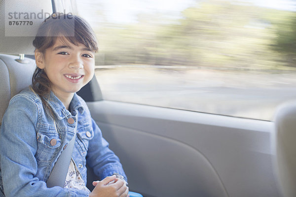 Porträt des glücklichen Mädchens auf dem Rücksitz des Autos