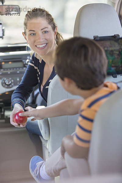 Mutter schenkt dem Jungen einen Apfel im Auto
