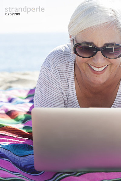 Glückliche Frau mit Laptop am Strand