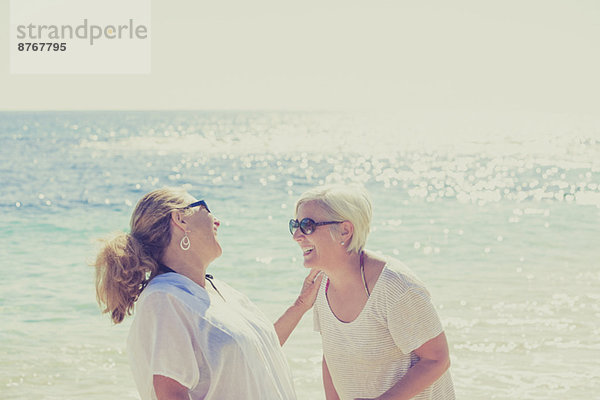Frauen lachen am sonnigen Strand
