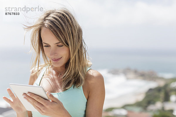 Frau mit digitalem Tablett mit Ozean im Hintergrund