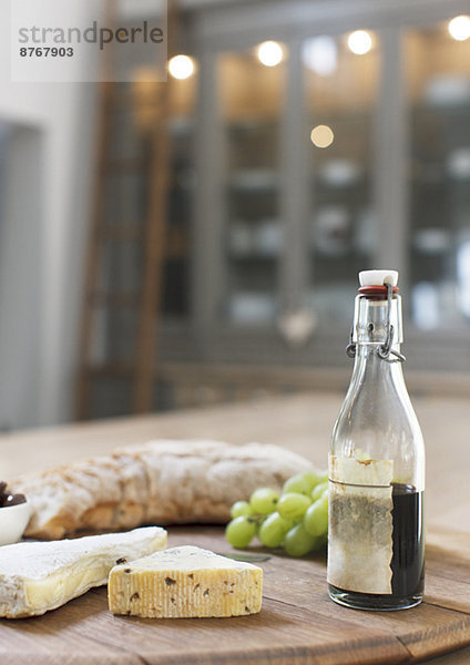 Käse  Balsamico-Essig  Trauben und Baguette auf Holzplatte