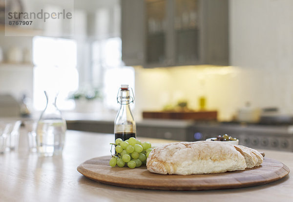 Baguette  Balsamico-Essig und Trauben auf Holzplatte in der Küche