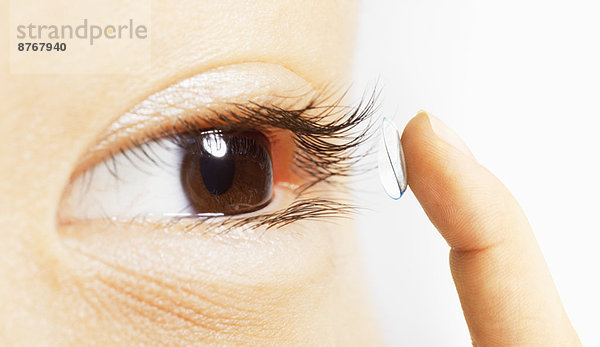 Extreme Nahaufnahme einer Frau  die eine Kontaktlinse ins Auge setzt.