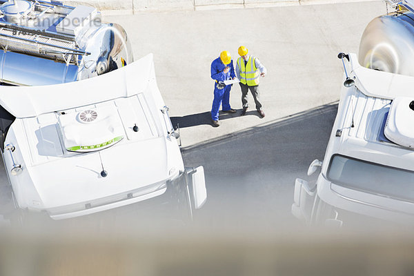 Arbeiter  die den Papierkram in der Nähe von Milchsammelwagen prüfen