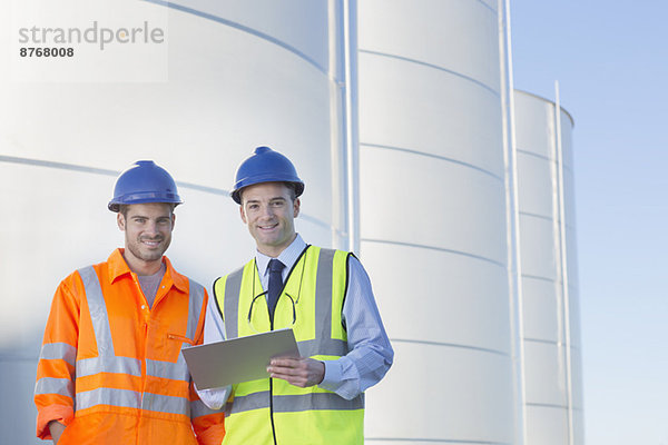 Porträt eines Geschäftsmannes und Arbeiters mit Zwischenablage in der Nähe von Silo-Lagertürmen