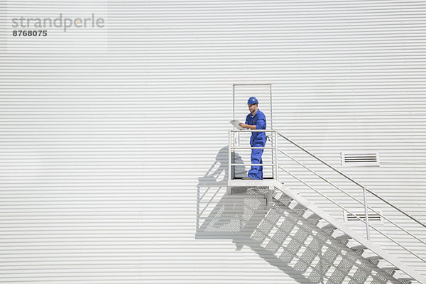 Arbeiter mit Klemmbrett auf der Treppe entlang des Gebäudes