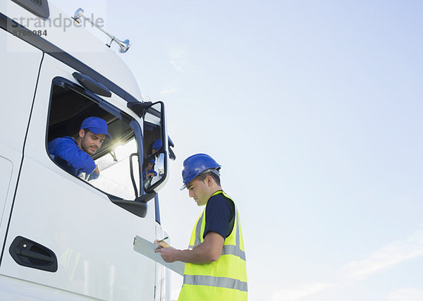 Arbeiter mit Zwischenablage im Gespräch mit dem LKW-Fahrer