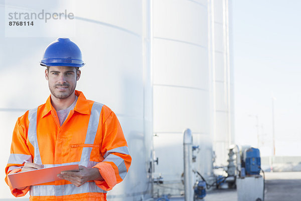 Portrait des Arbeiters mit Zwischenablage in der Nähe von Silo-Lagertürmen