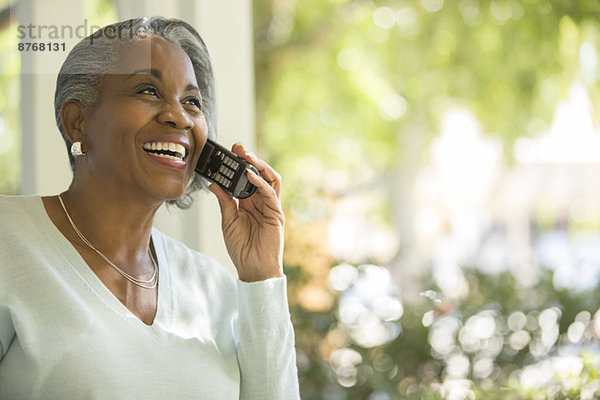 Glückliche Seniorin am Telefon im Freien