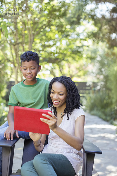 Mutter und Sohn mit digitalem Tablett im Freien