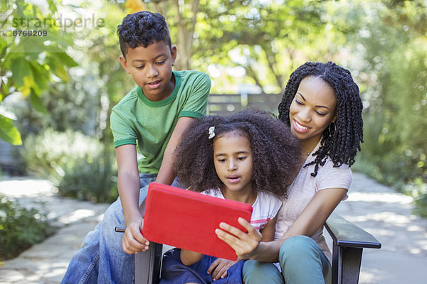 Mutter und Kinder  die ein digitales Tablett im Freien benutzen
