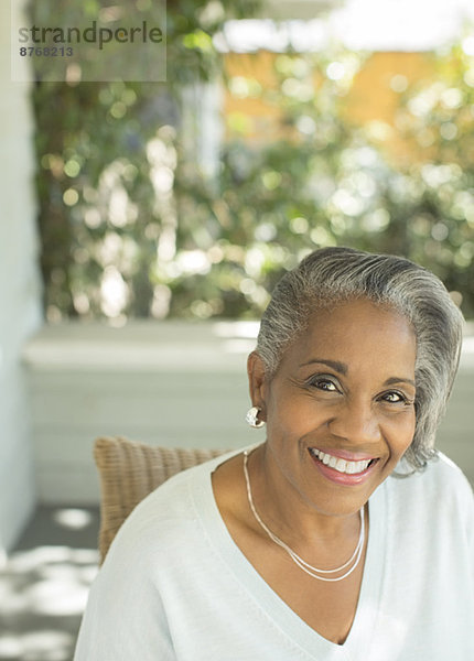 Porträt einer lächelnden Seniorin auf der Veranda